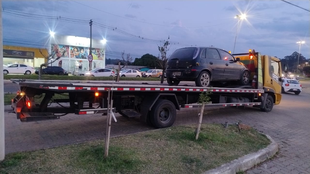 Chevrolet Corsa preto sendo transportado por guincho ao entardecer