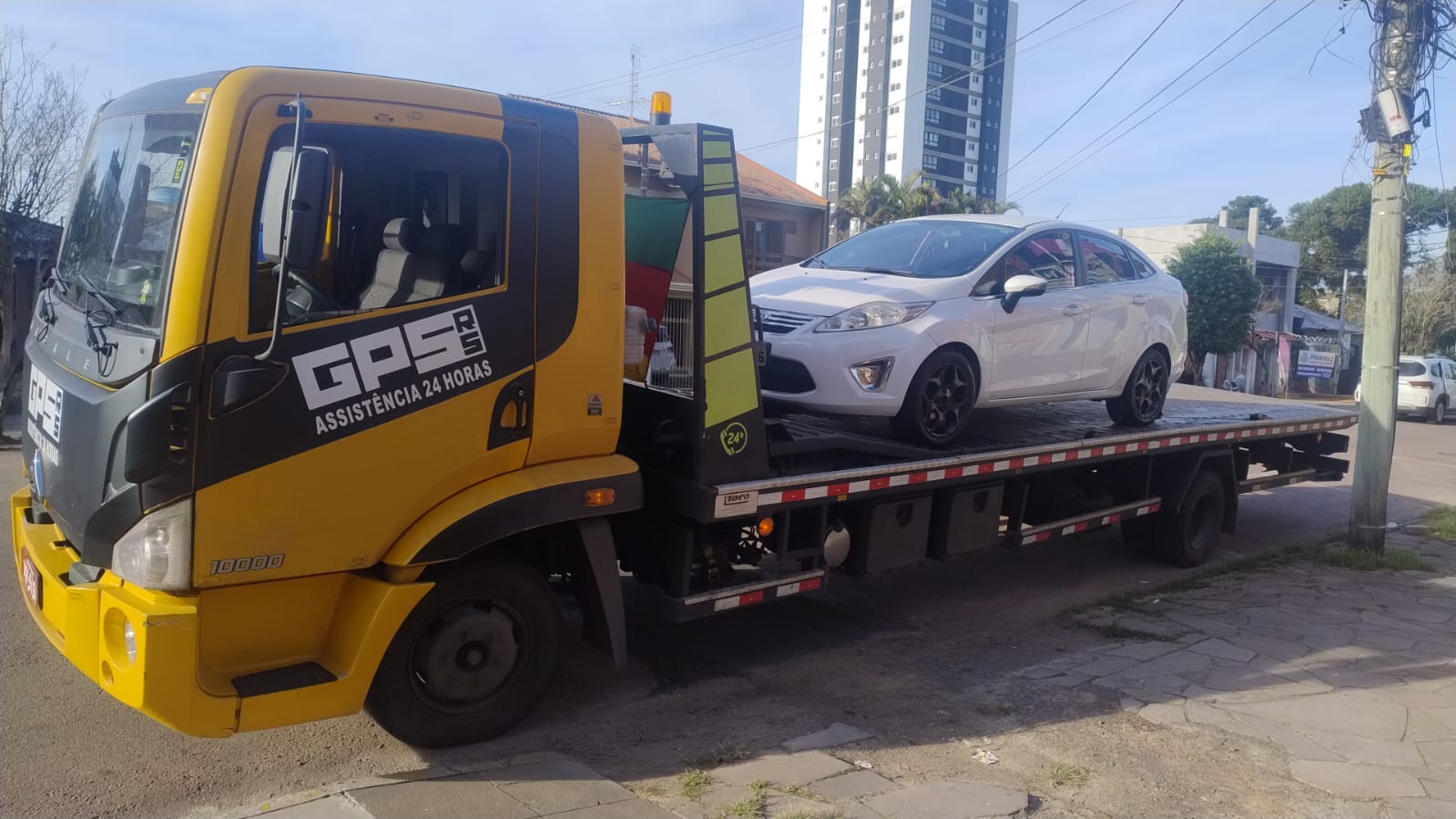 Ford Fiesta branco sendo transportado por guincho